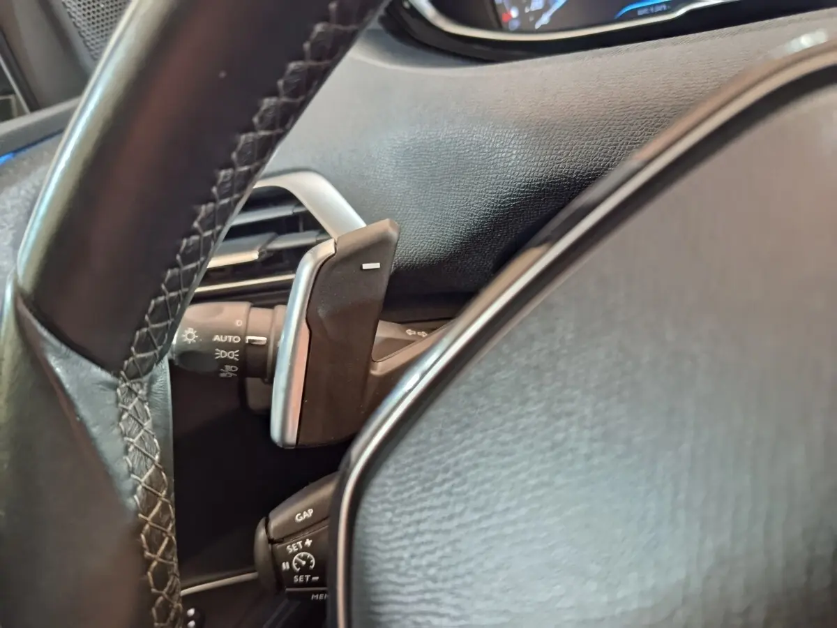 Gros plan sur le volant cuir noir du Peugeot 3008 avec palettes de commande et commandes de régulateur de vitesse.