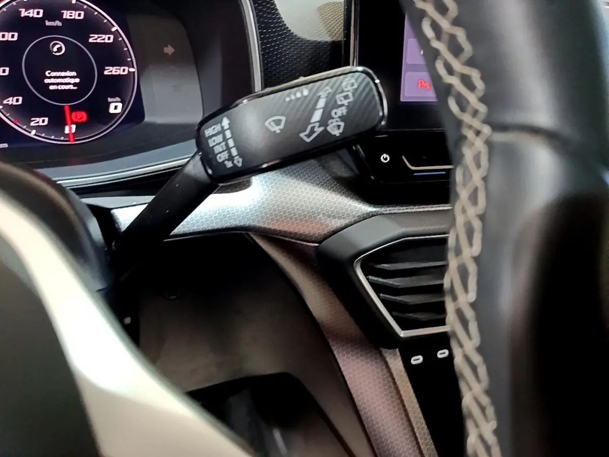 Gros plan intérieur sur le combiné d'instruments et la commande d'essuie-glace du SEAT Leon 2023, volant partiellement visible.