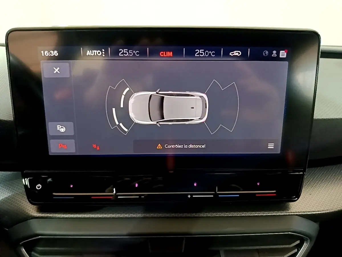 Écran tactile central montrant l'aide au stationnement avec vue aérienne d'une SEAT Leon gris clair, tableau de bord moderne.