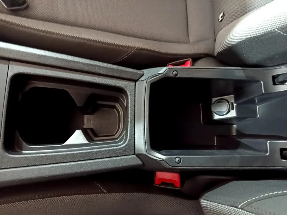 Vue plongeante sur la console centrale noire avec porte-gobelets et rangement du SEAT Leon gris clair 2023.