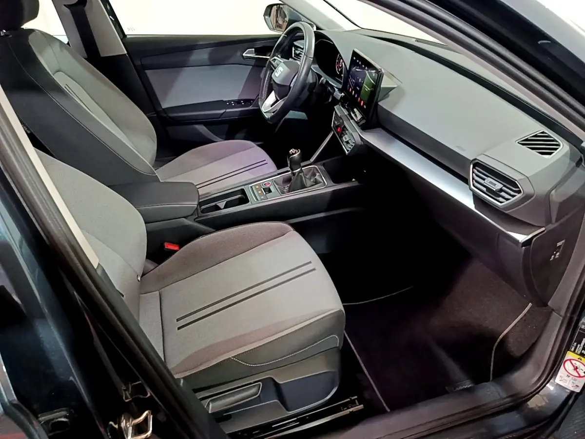 Vue intérieure côté conducteur de la SEAT LEON gris clair 2023 avec tableau de bord moderne et boîte manuelle.