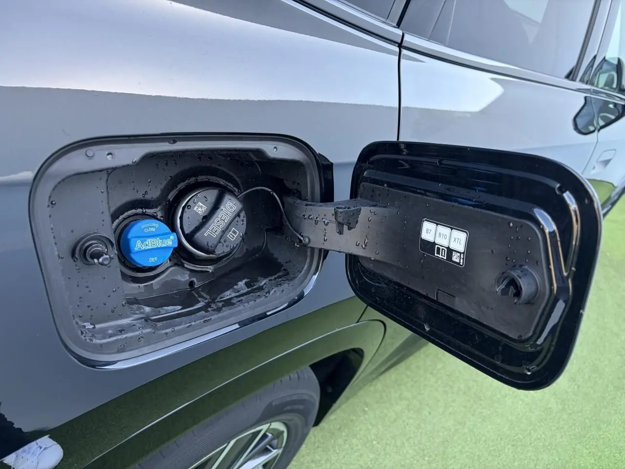 Bouchon de réservoir diesel et AdBlue ouvert sur le côté gauche d'une BMW X1 noir saphir, vue rapprochée.