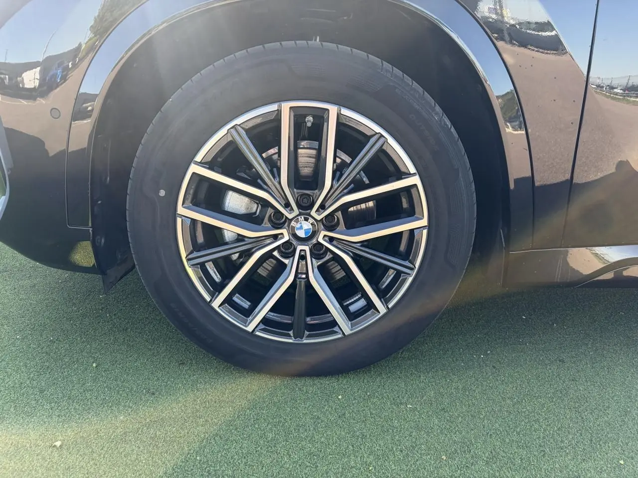 Gros plan sur la roue avant gauche du BMW X1 noir saphir, mettant en valeur la jante alliage 18 pouces bicolore style 838 M.