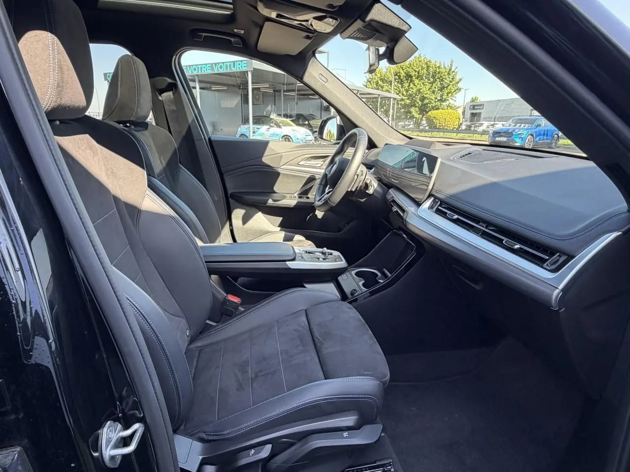 Intérieur avant droit de la BMW X1 noir saphir, sièges sport Alcantara, tableau de bord moderne avec écran tactile incurvé.
