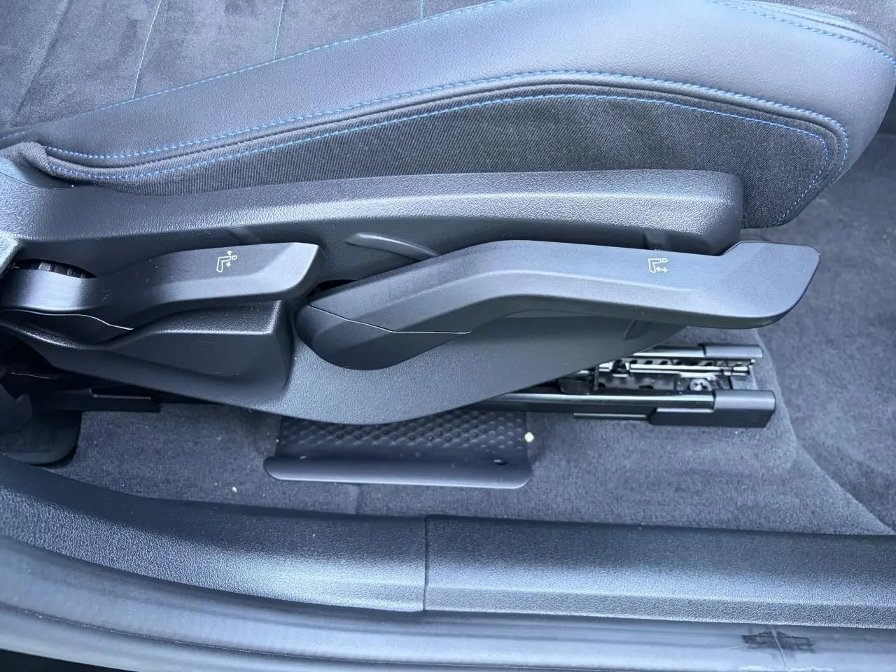 Gros plan sur les commandes latérales du siège avant en Alcantara noir avec surpiqûres bleues du BMW X1 noir Saphir 2025.