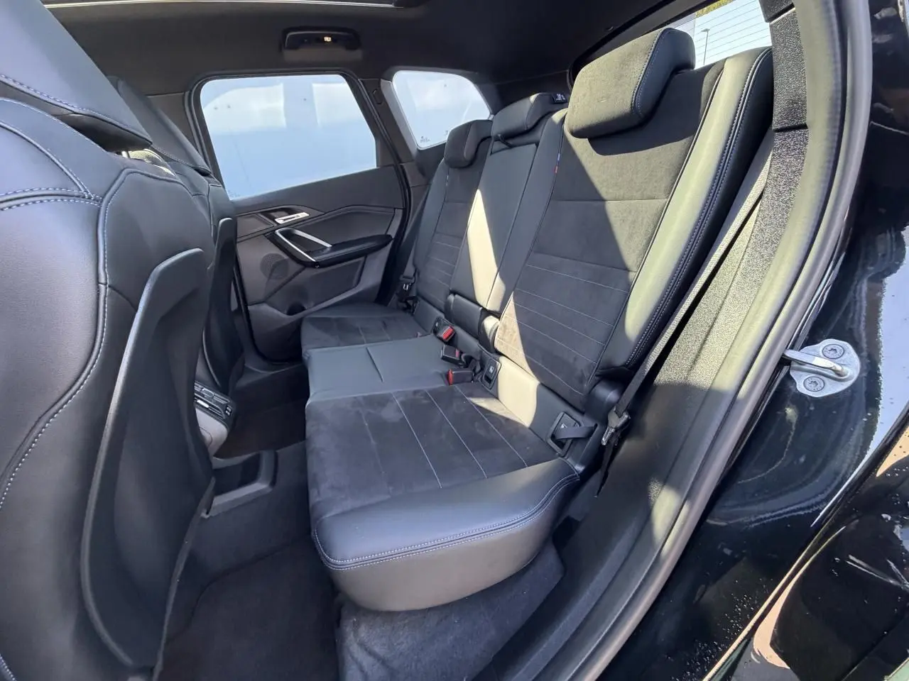 Vue intérieure côté droit sur la banquette arrière en Alcantara noir avec surpiqûres bleues du BMW X1 noir saphir.