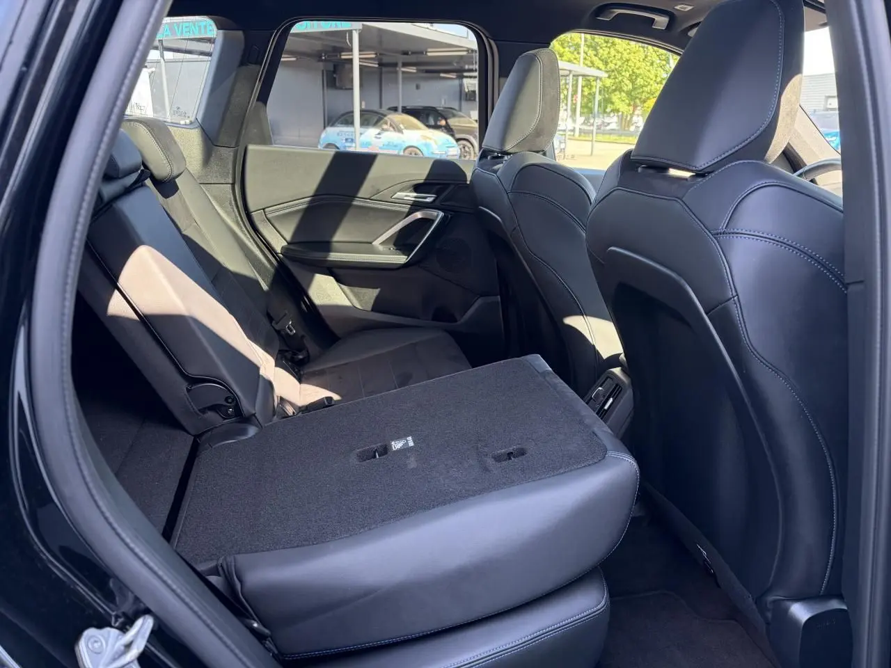 Vue intérieure côté gauche de la banquette arrière noire rabattue partiellement dans un BMW X1 noir Saphir 2025.