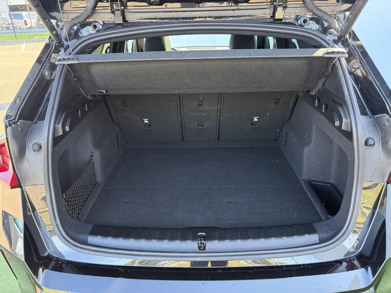 Coffre ouvert vu de l'arrière d'un BMW X1 noir saphir avec filet de séparation et banquette arrière rabattable.