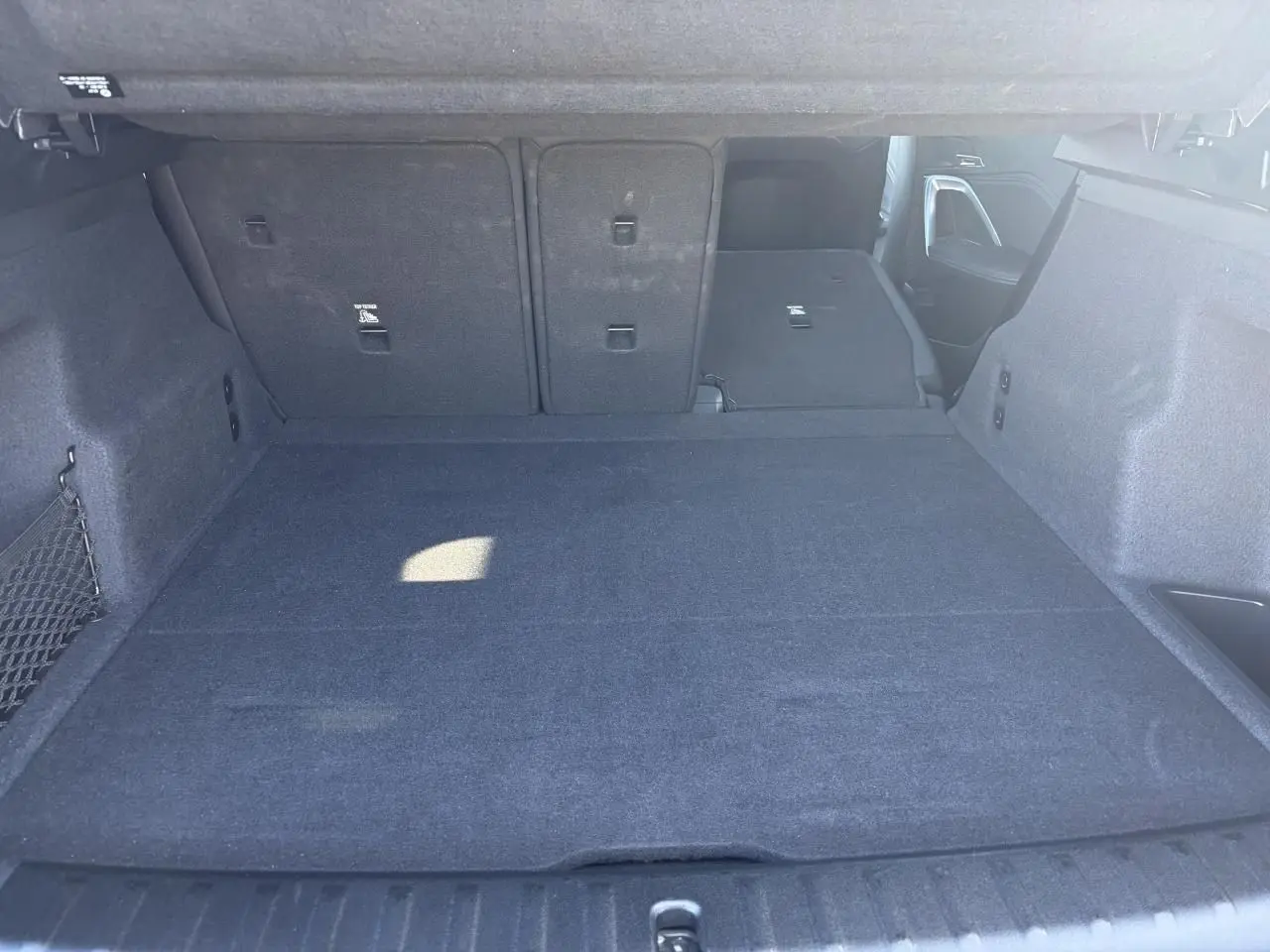 Coffre spacieux de BMW X1 noir Saphir, vue intérieure arrière avec banquette arrière partiellement rabattue.