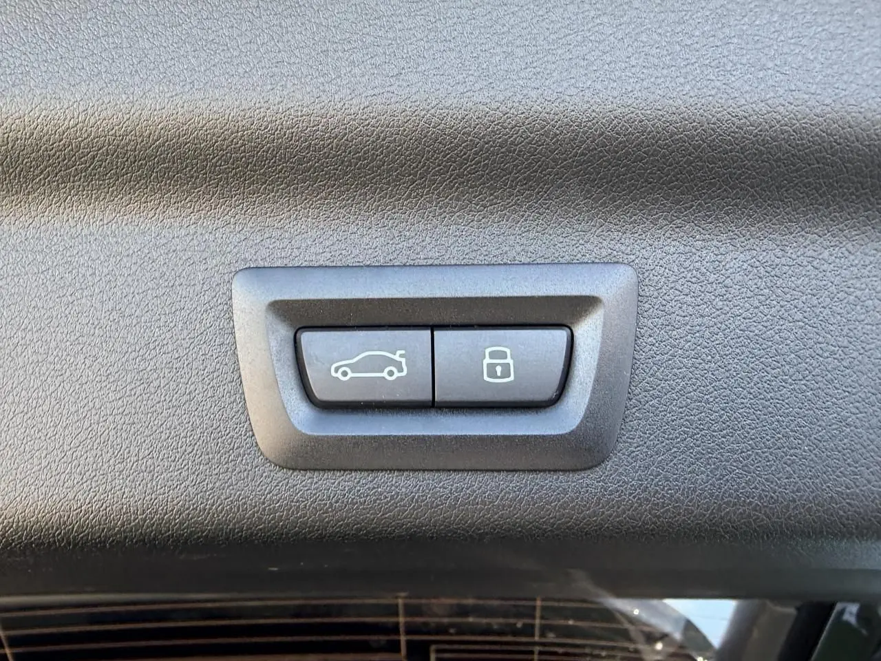 Boutons de commande du hayon et de verrouillage intégrés dans le panneau intérieur noir du coffre d'un BMW X1 noir Saphir.