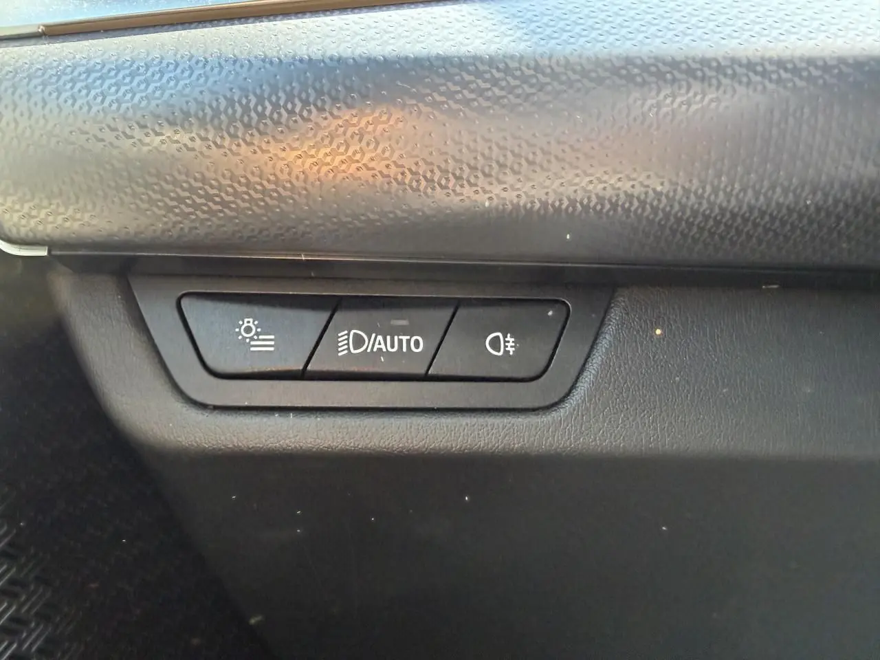 Gros plan sur les commandes d'éclairage intérieures noires du BMW X1 noir Saphir, version 2025.