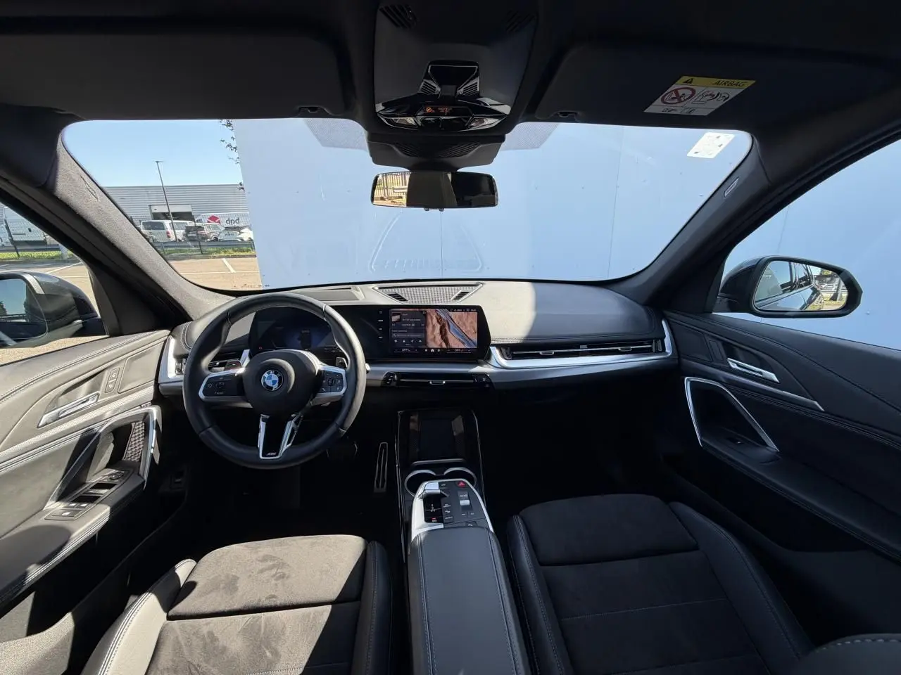 Vue intérieure avant du BMW X1 noir Saphir 2025, mettant en valeur le tableau de bord digital et le volant M cuir.