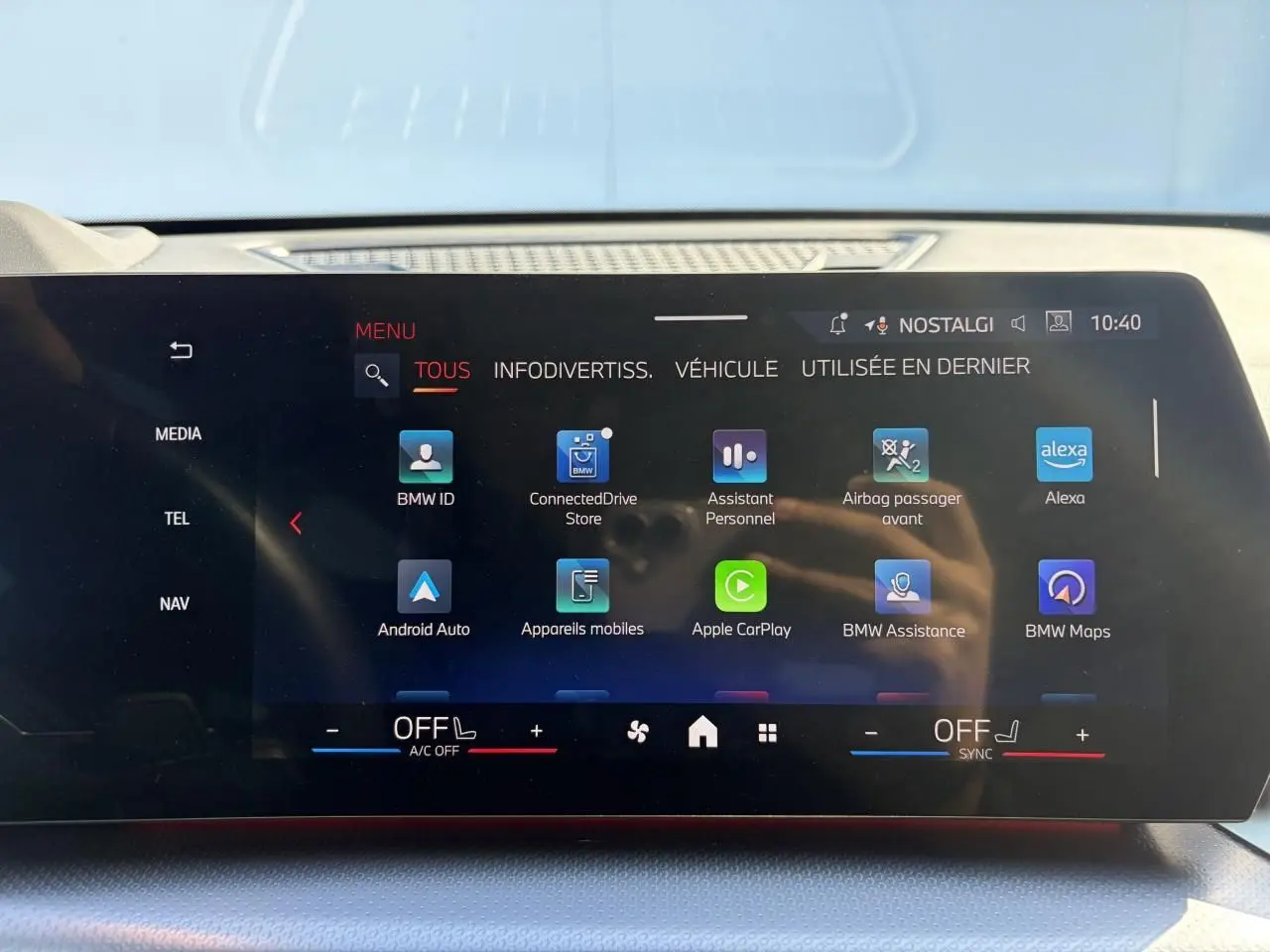 Écran tactile incurvé du tableau de bord du BMW X1 noir, affichant les applications connectées et options multimédia.