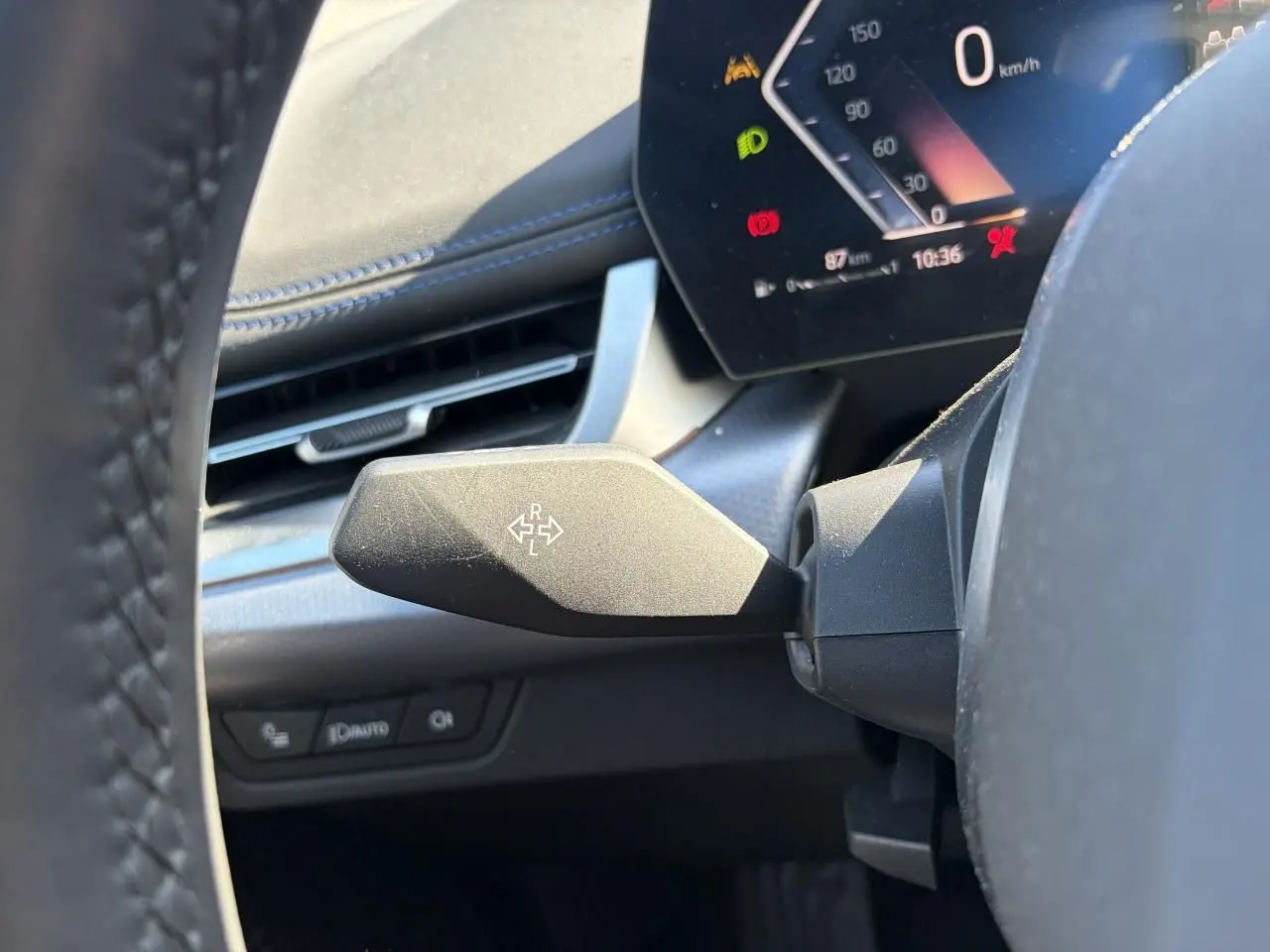 Gros plan sur le commodo gauche noir mat et le combiné d'instruments digital du BMW X1 noir Saphir, vue depuis le siège conducteur.