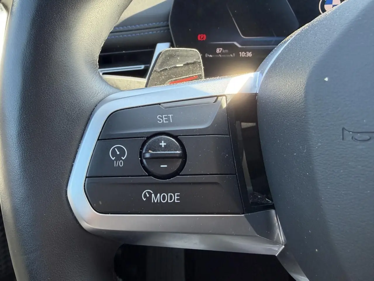 Gros plan sur les commandes de régulateur de vitesse au volant cuir du BMW X1 noir Saphir 2025.