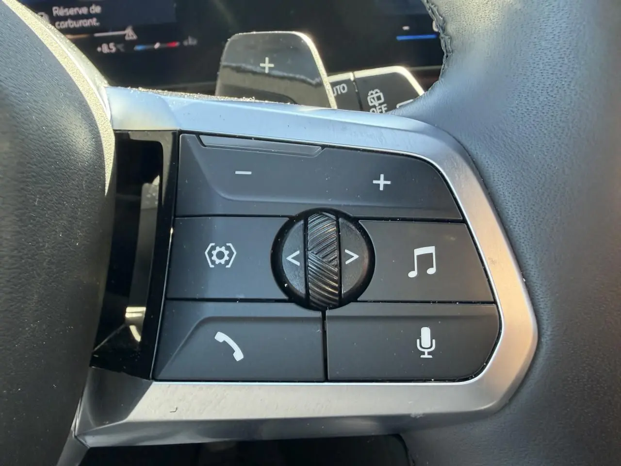 Gros plan sur les commandes multifonctions du volant cuir noir du BMW X1 2025, avec boutons de volume et appels.