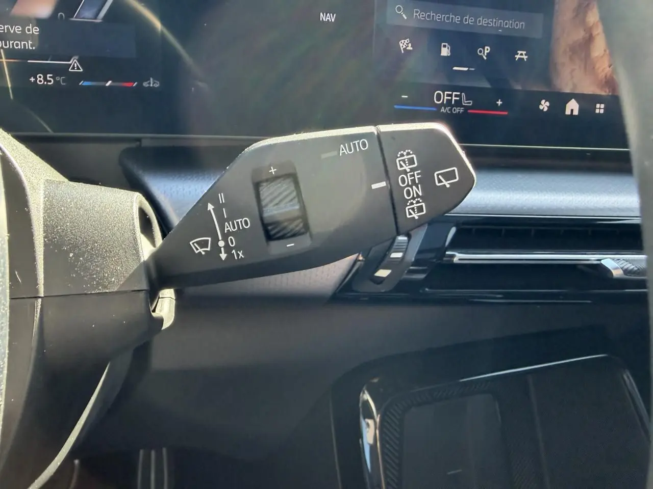 Gros plan sur la commande d’essuie-glace à gauche du volant dans l’habitacle noir du BMW X1 2025.