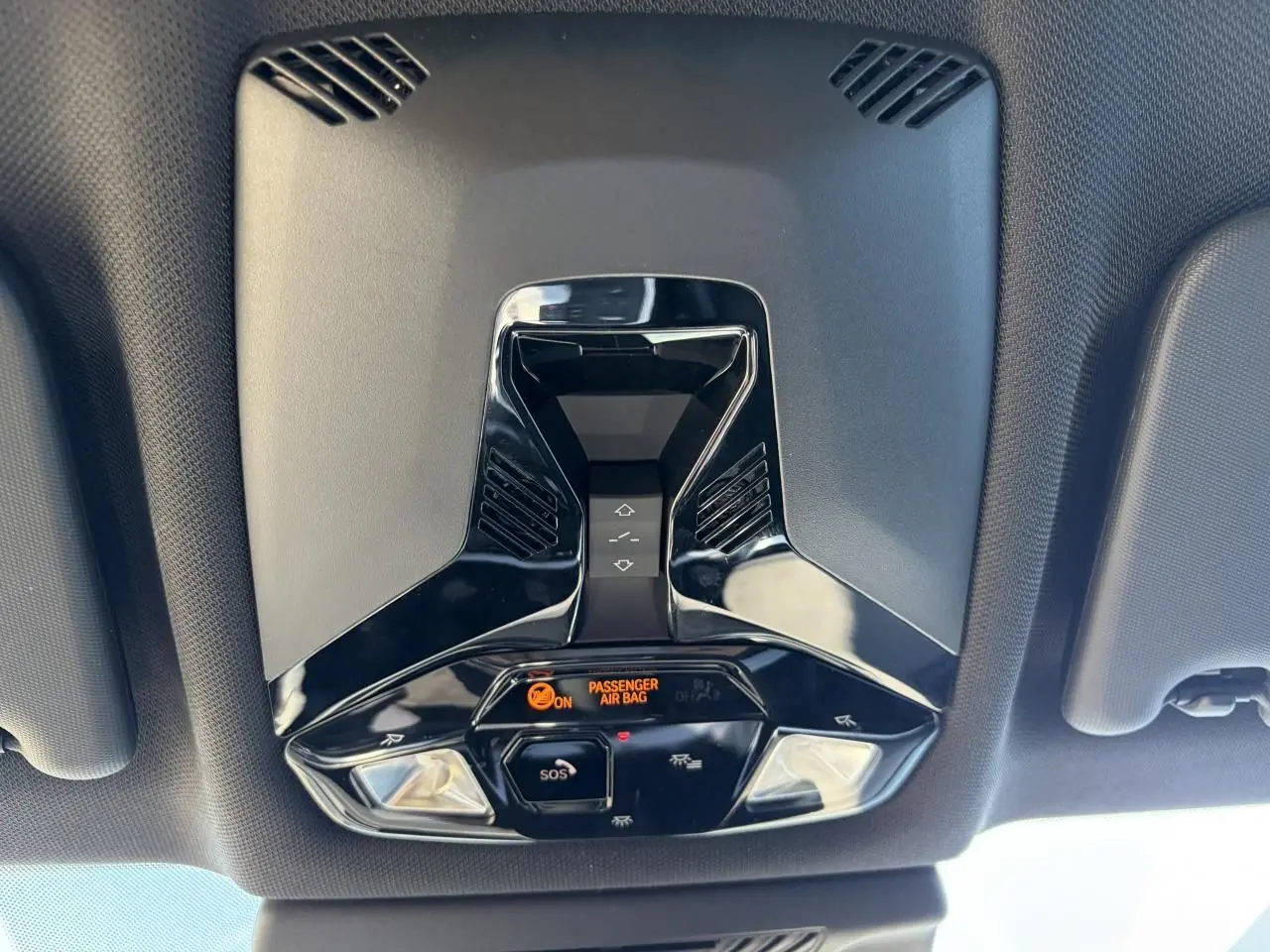 Vue en contre-plongée du plafonnier noir brillant avec commandes et indicateur airbag du BMW X1 noir Saphir 2025.