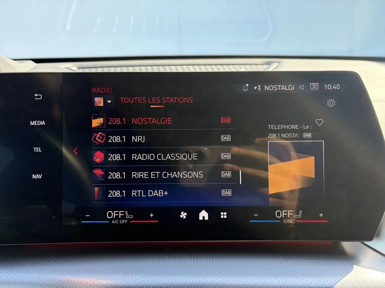Écran tactile incurvé de la BMW X1 noir saphir, affichant la liste des stations radio en mode DAB.