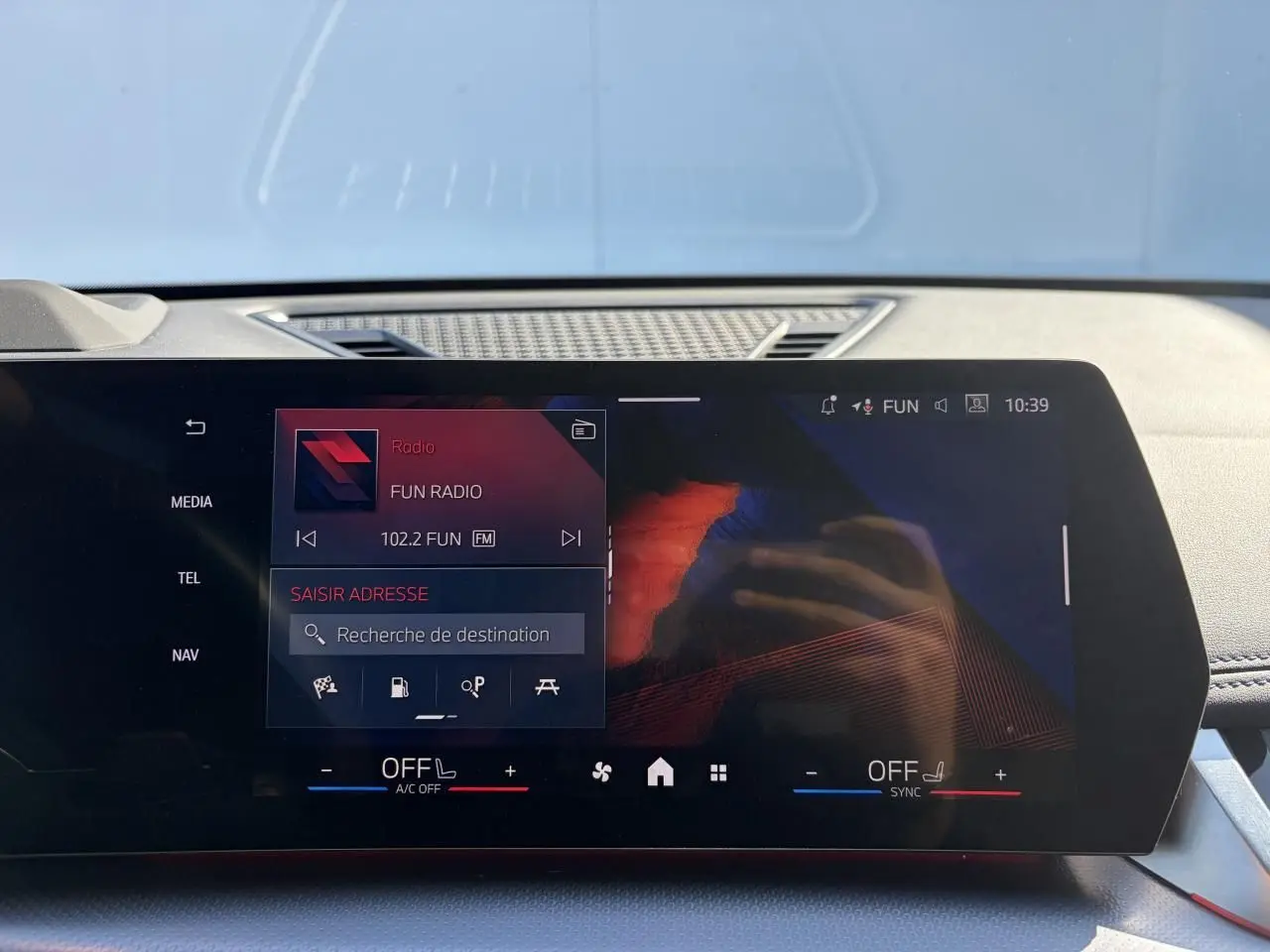 Écran tactile incurvé du tableau de bord de la BMW X1 noir Saphir, affichant la radio et la navigation.