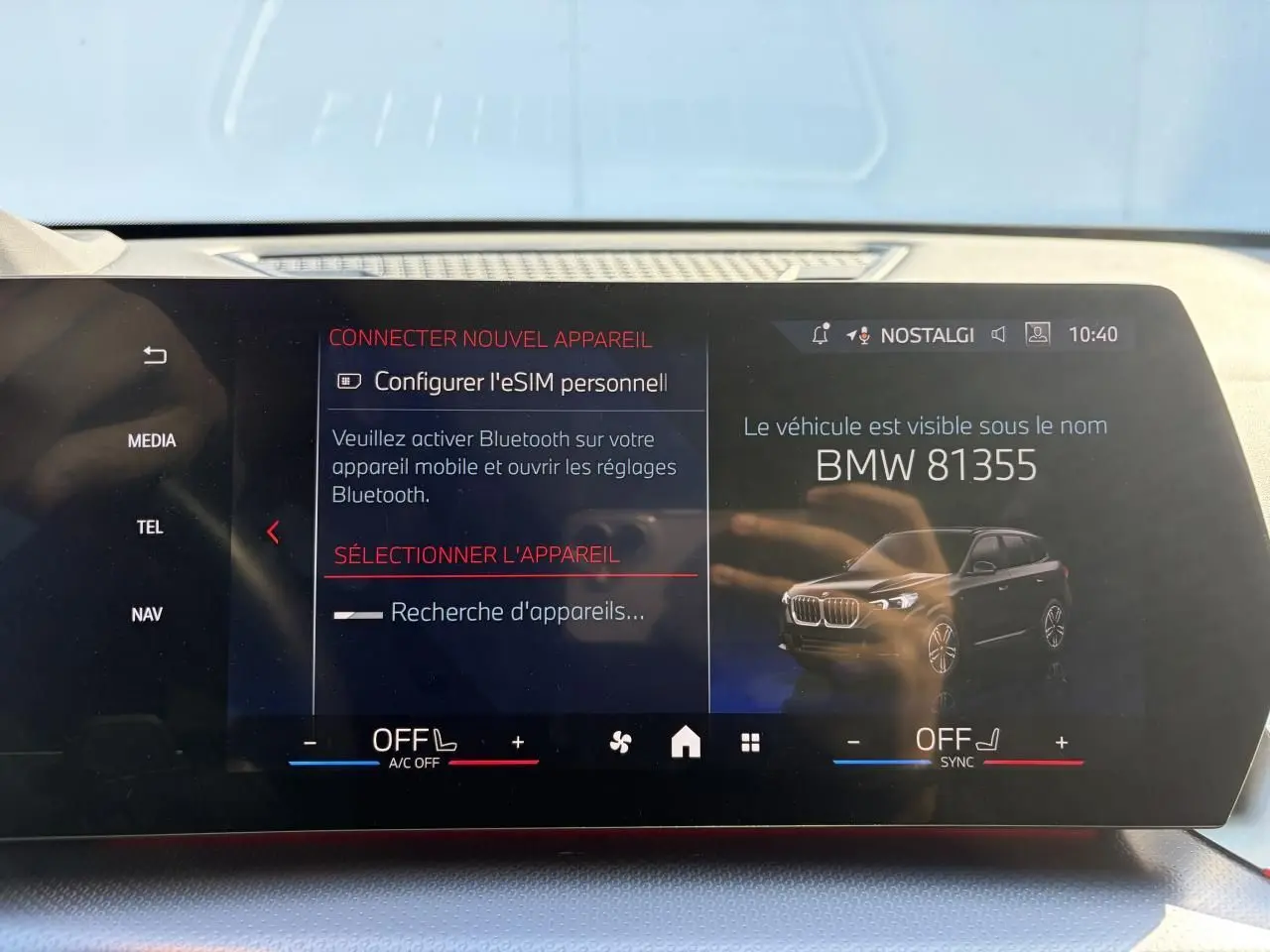 Écran tactile intérieur montrant une image 3/4 avant d’un BMW X1 noir Saphir avec interface connectivité Bluetooth.