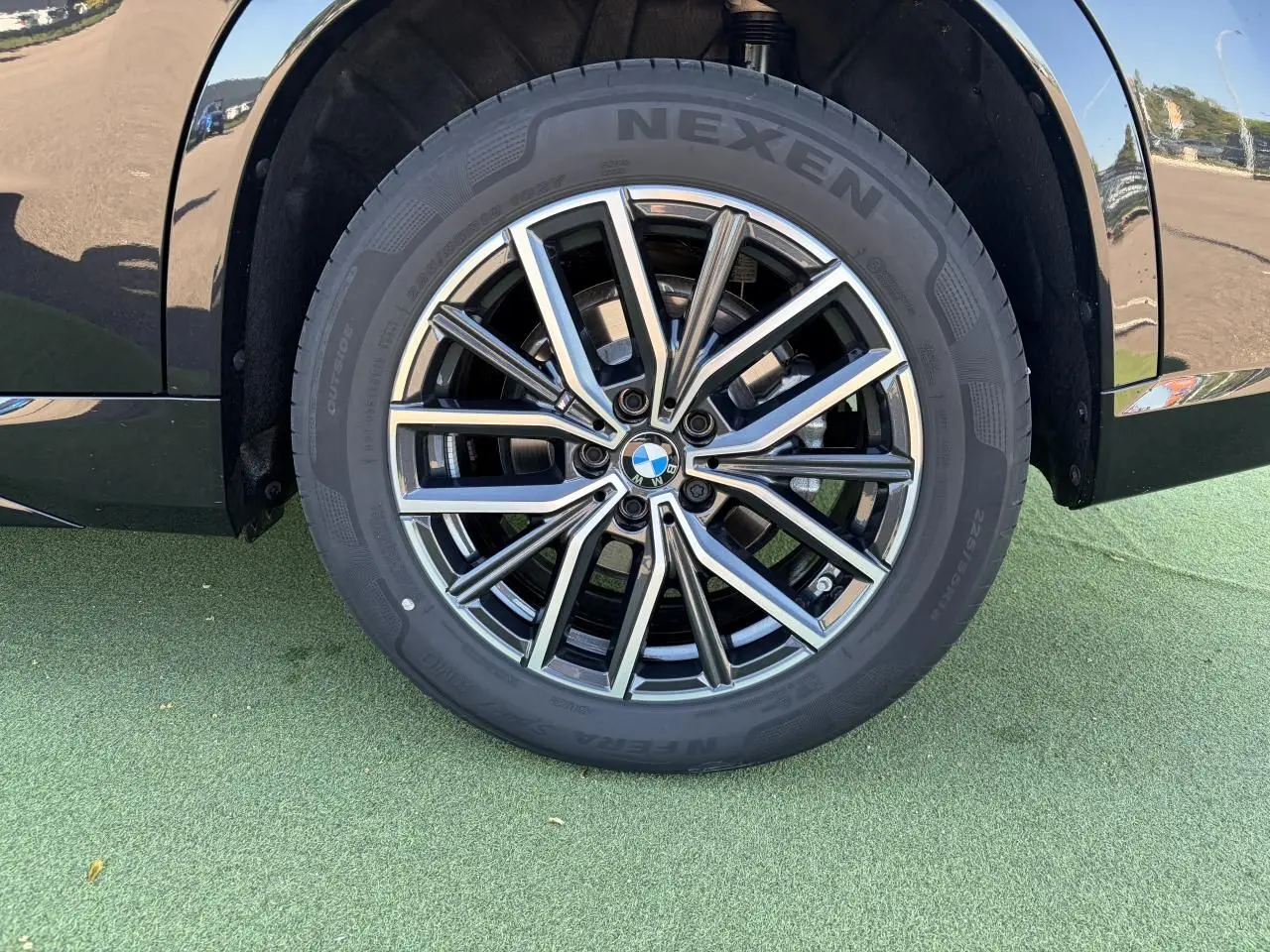 Gros plan sur la roue avant droite du BMW X1 noir saphir, mettant en valeur la jante alliage 18 pouces style 838 M bicolore.