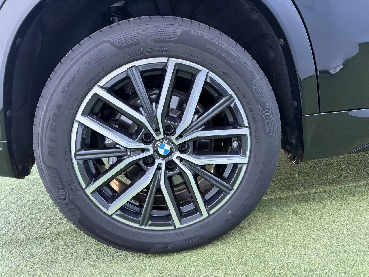 Gros plan sur la roue avant droite du BMW X1 noir saphir, mettant en valeur la jante alliage 18 pouces style 838 M bicolore.