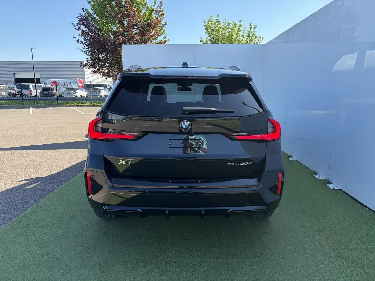 Vue arrière d’une BMW X1 noire Saphir 2025 avec feux LED distinctifs et toit ouvrant panoramique visible.