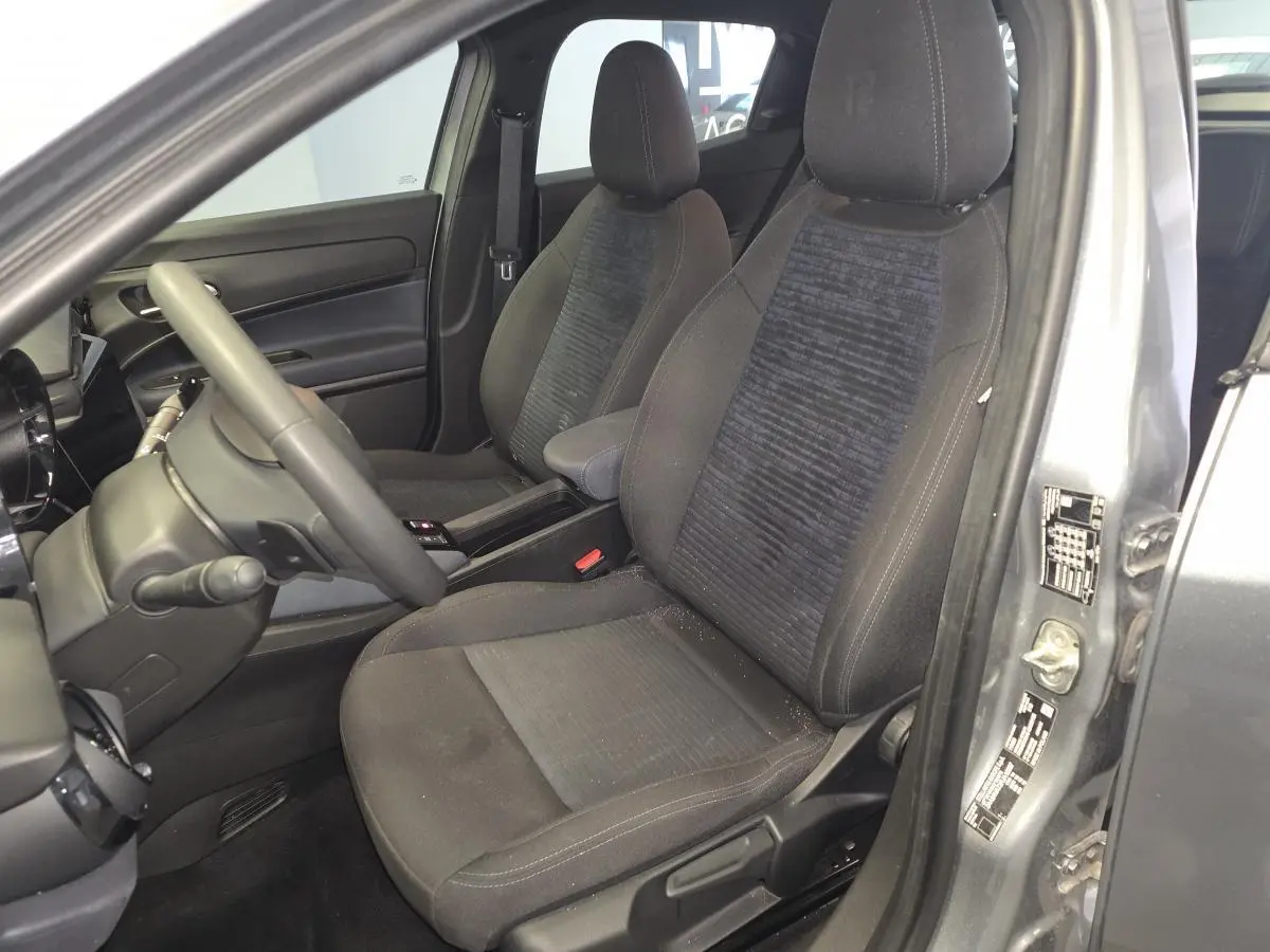 Vue intérieure côté conducteur de l'Alfa Romeo Junior 1.2 Ibrida gris, montrant les sièges avant et le volant multifonctions.