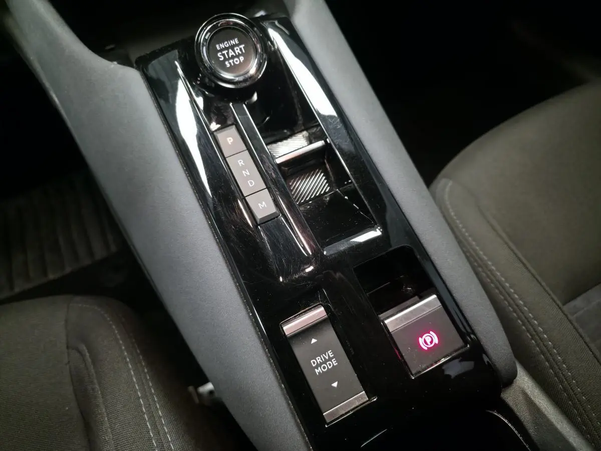 Vue rapprochée de la console centrale noire brillante avec sélecteur de mode de conduite et frein de parking électrique de l'Alfa Romeo Junior 1.2 Ibrida.