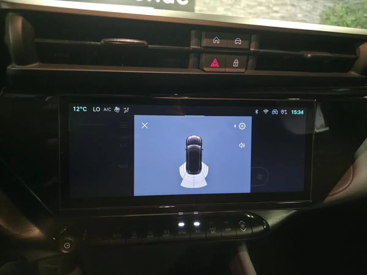 Écran tactile central de l'Alfa Romeo Junior 1.2 Ibrida 2025 montrant l'aide au stationnement en vue de dessus.