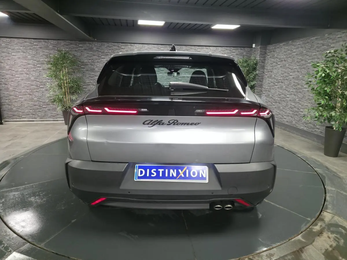 Vue arrière d'une Alfa Romeo Junior 1.2 Ibrida gris métallisé avec feux arrière LED et double sortie d'échappement.