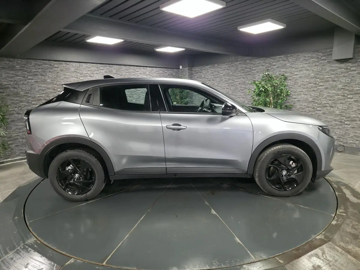 Vue de profil côté gauche d'une Alfa Romeo Junior 1.2 Ibrida gris métallisé avec jantes noires et toit noir.