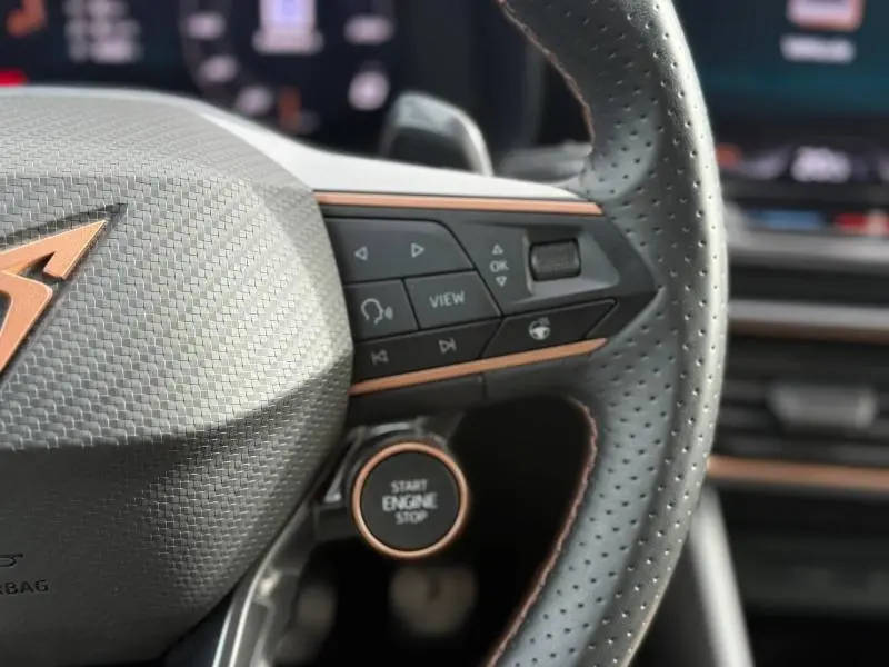 Gros plan sur le volant perforé noir du CUPRA Formentor blanc Nevada, avec commandes intégrées et bouton Start Engine Stop.