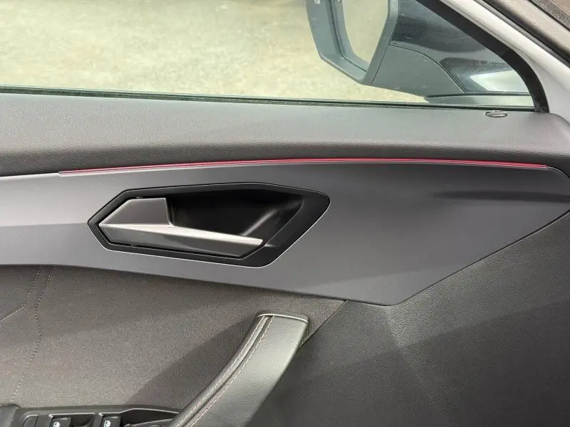 Détail de la porte côté conducteur du CUPRA Formentor blanc Nevada, avec poignée argentée et bande lumineuse rouge.