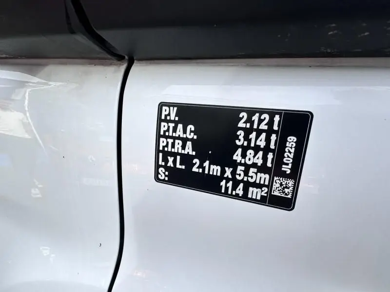 Détail de l'autocollant noir indiquant les poids et dimensions sur la porte blanche côté gauche du Ford Transit Fourgon 2019.
