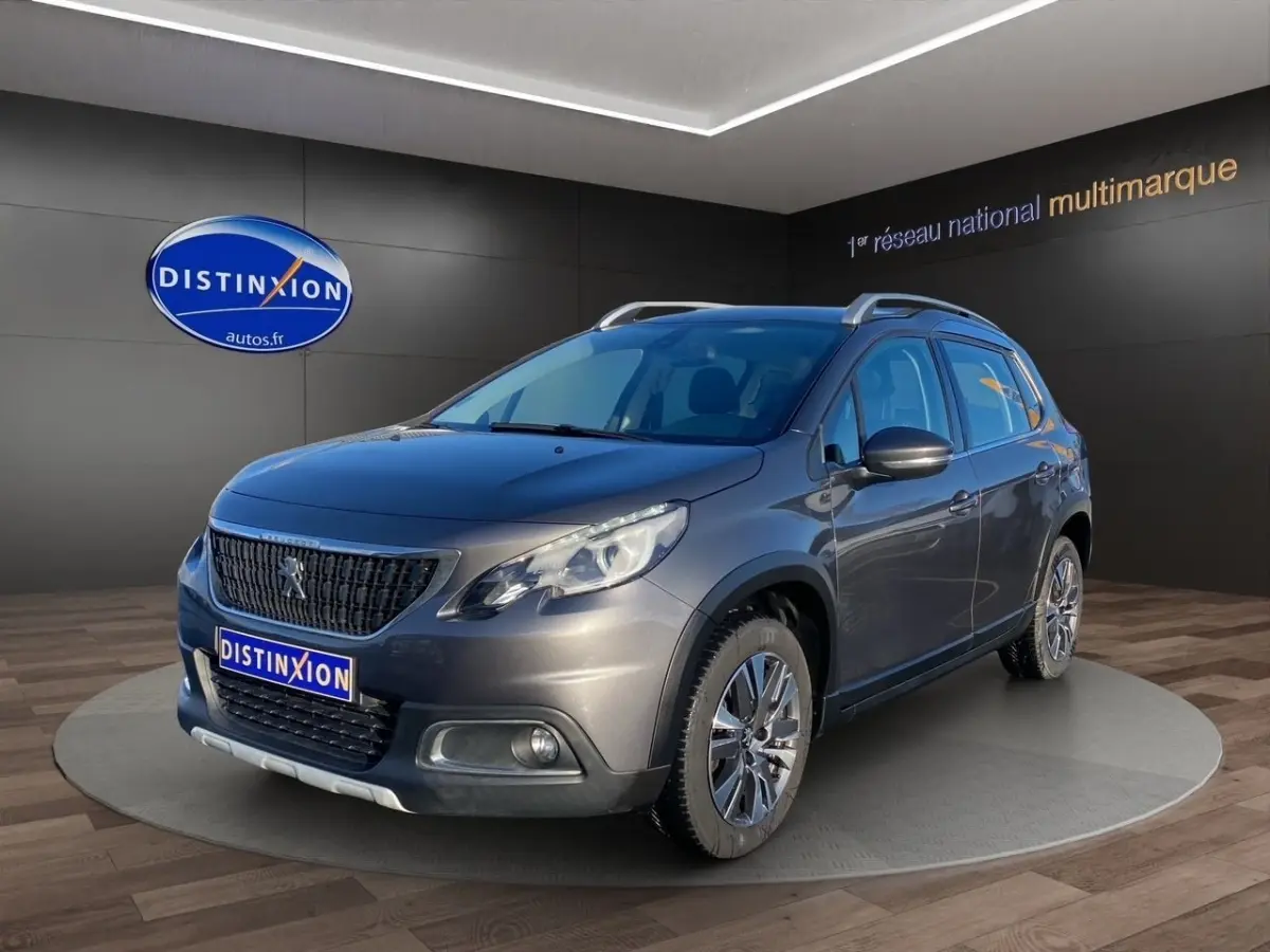 Peugeot 2008 gris foncé vue 3/4 avant droit avec toit ouvrant et jantes alliage en showroom.