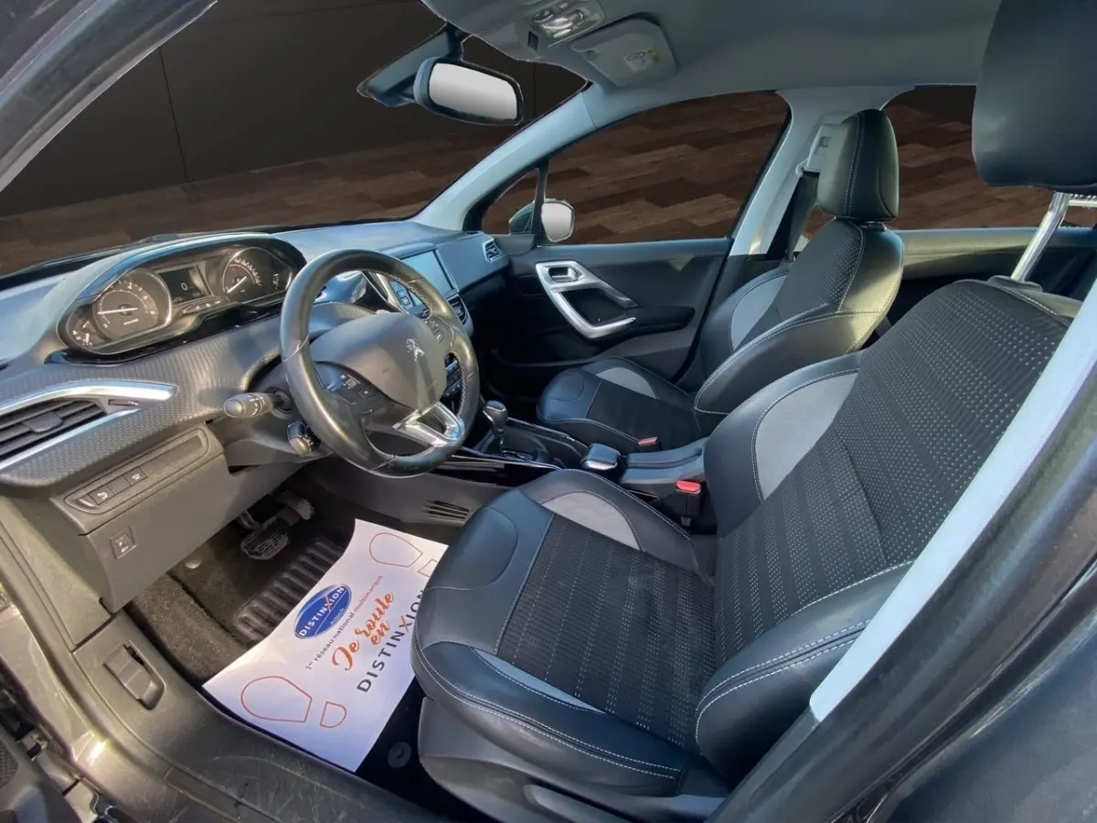 Vue intérieure côté conducteur du Peugeot 2008 gris foncé, montrant les sièges en cuir et le tableau de bord moderne.