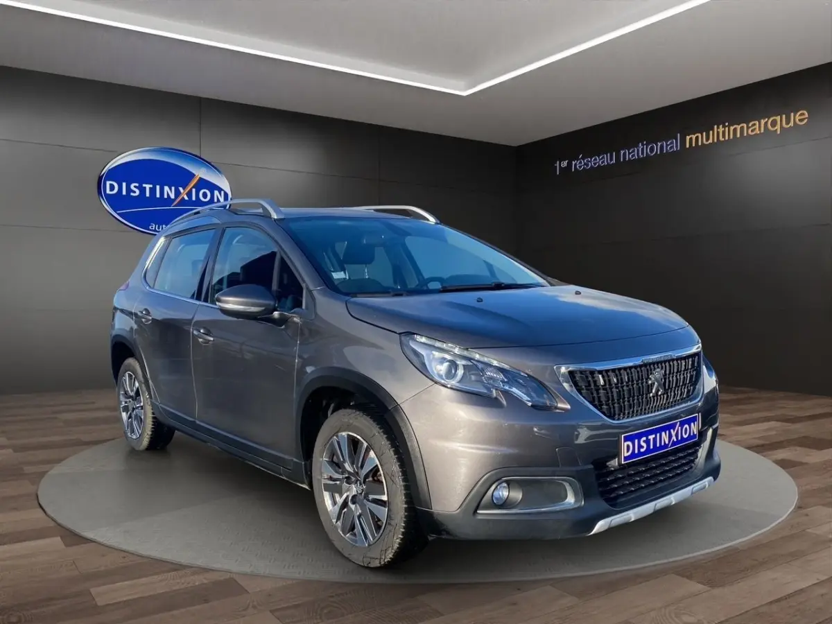 Peugeot 2008 gris foncé vue 3/4 avant droit, avec toit ouvrant et jantes alliage distinctives.