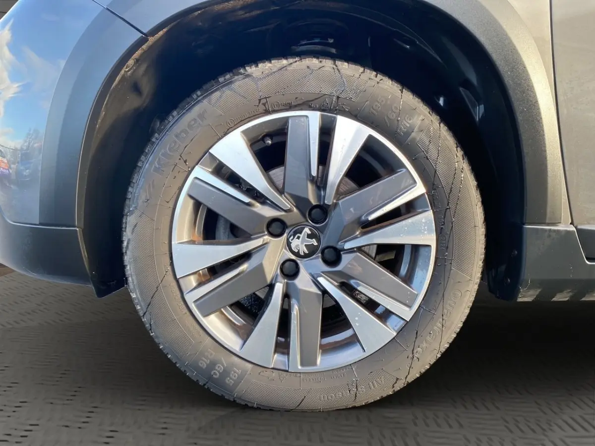Gros plan sur la roue avant droite avec jante alliage gris et partie de la carrosserie gris foncé du Peugeot 2008.