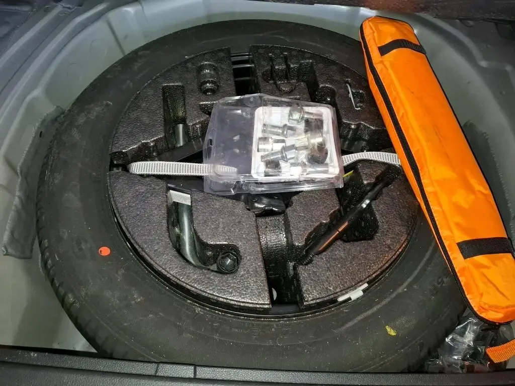 Vue rapprochée de la roue de secours et des outils de bord dans le coffre du SEAT Arona gris foncé 2021.