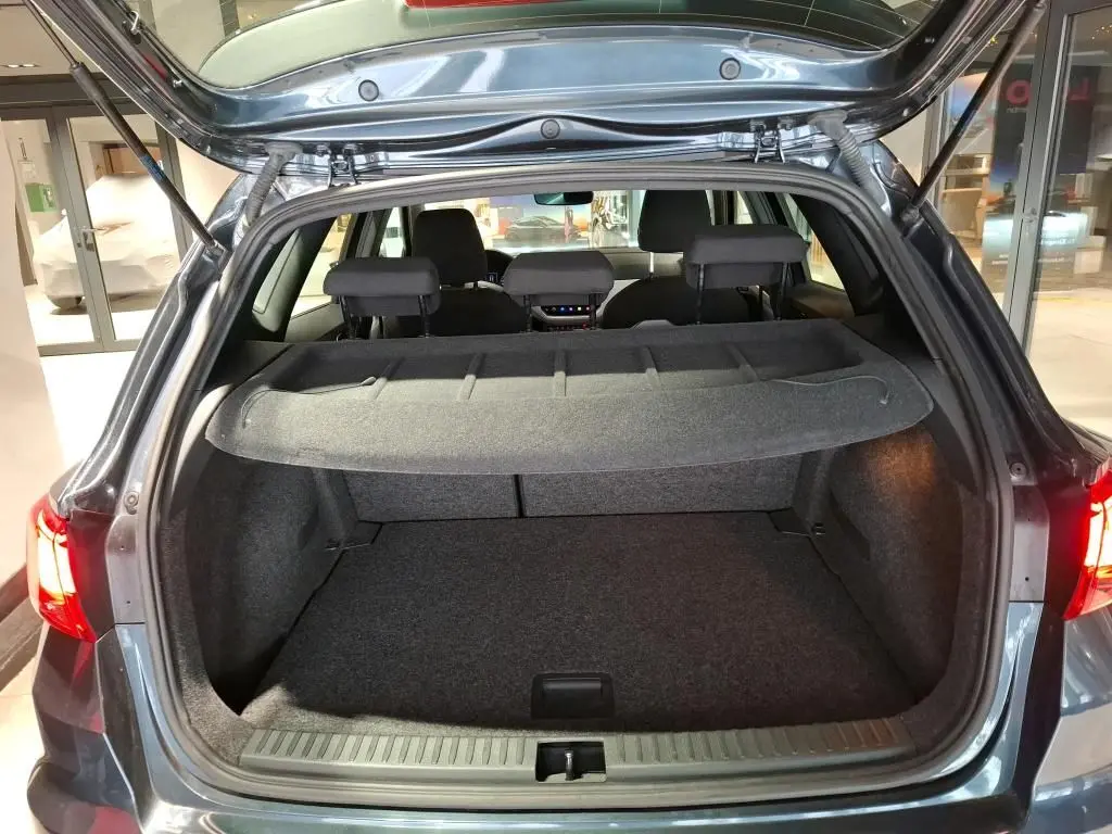 Vue arrière du coffre ouvert d'un SEAT Arona gris foncé 2021, mettant en valeur l'espace de chargement et la tablette cache-bagages.