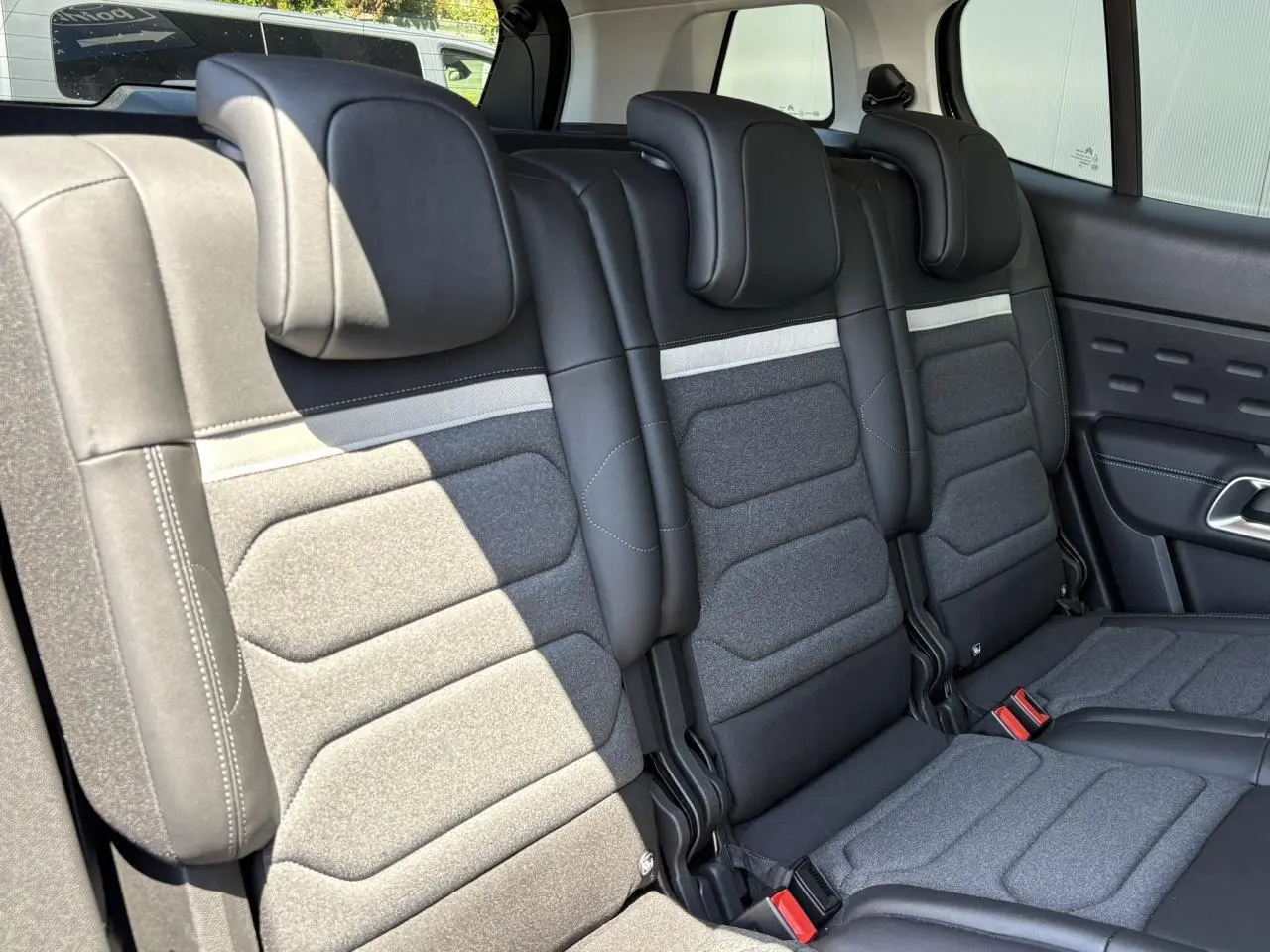 Vue rapprochée des trois sièges arrière indépendants en tissu gris et cuir noir du Citroën C5 Aircross Hybrid 2025.