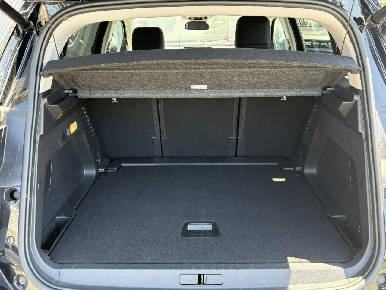 Coffre ouvert vu de l'arrière d'un Citroën C5 Aircross Hybrid noir Perla avec hayon électrique et cache-bagages relevé.