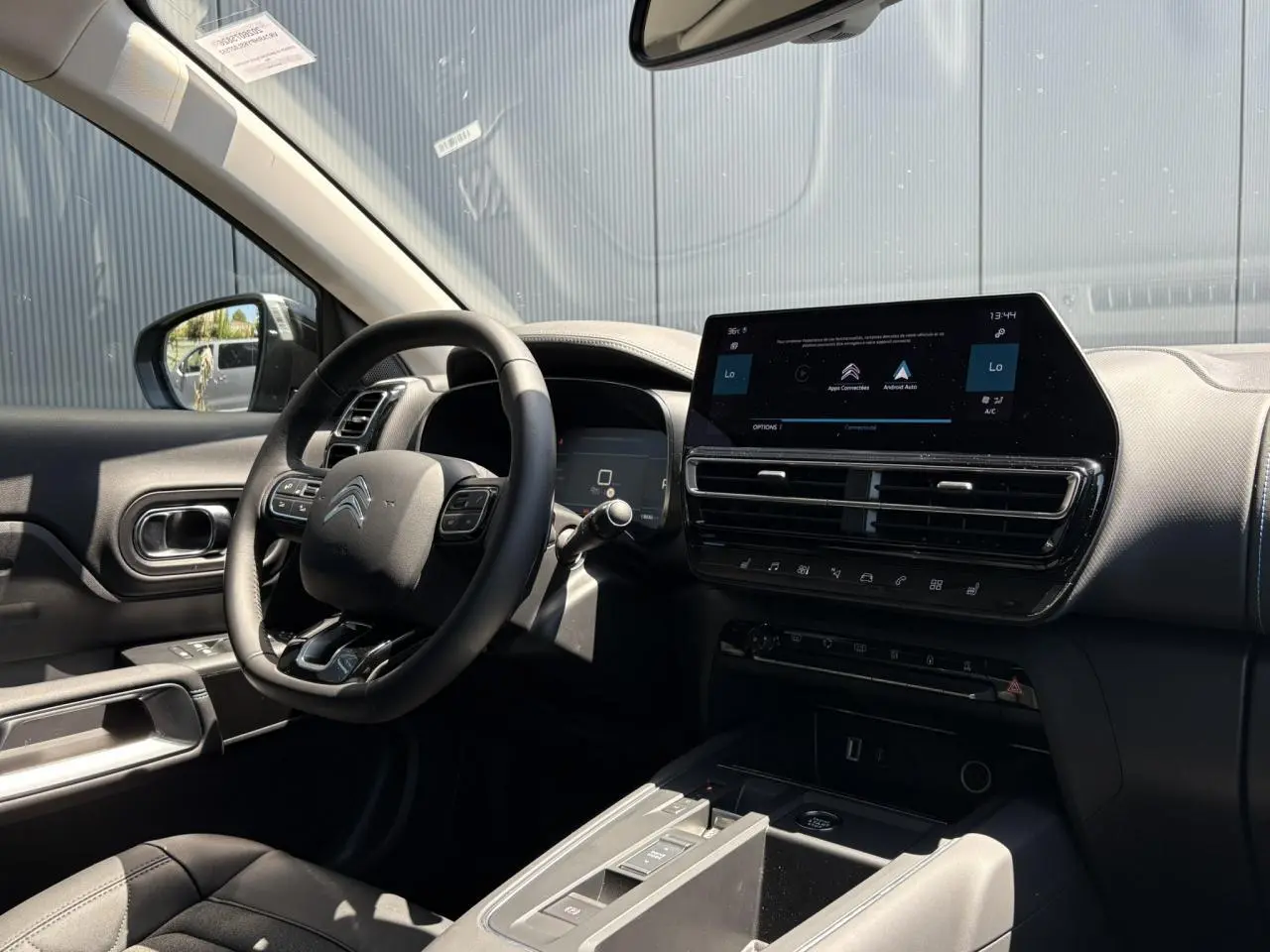Intérieur noir de la Citroën C5 Aircross Hybrid 2025, vue côté conducteur sur volant et écran tactile central.