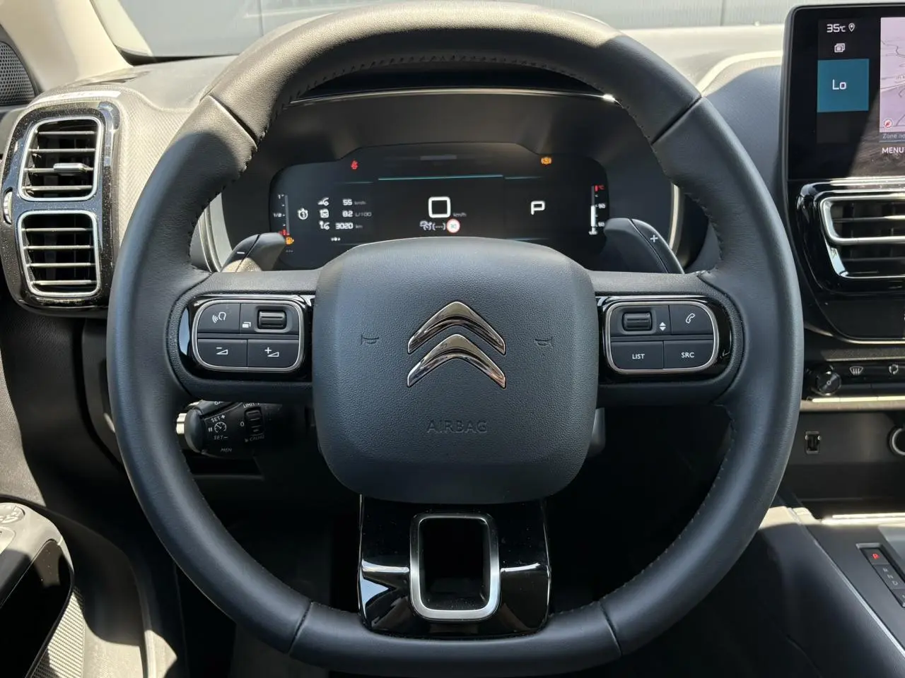 Vue frontale du volant noir du Citroën C5 Aircross Hybrid 2025 avec commandes intégrées et tableau de bord numérique.