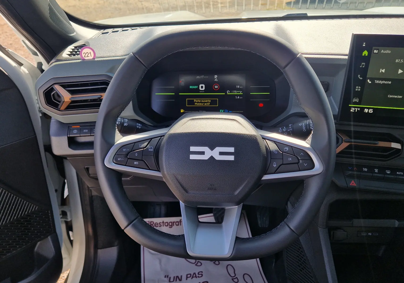 Vue intérieure centrée sur le volant du Dacia Duster blanc 2026, avec tableau de bord numérique et écran tactile visible.
