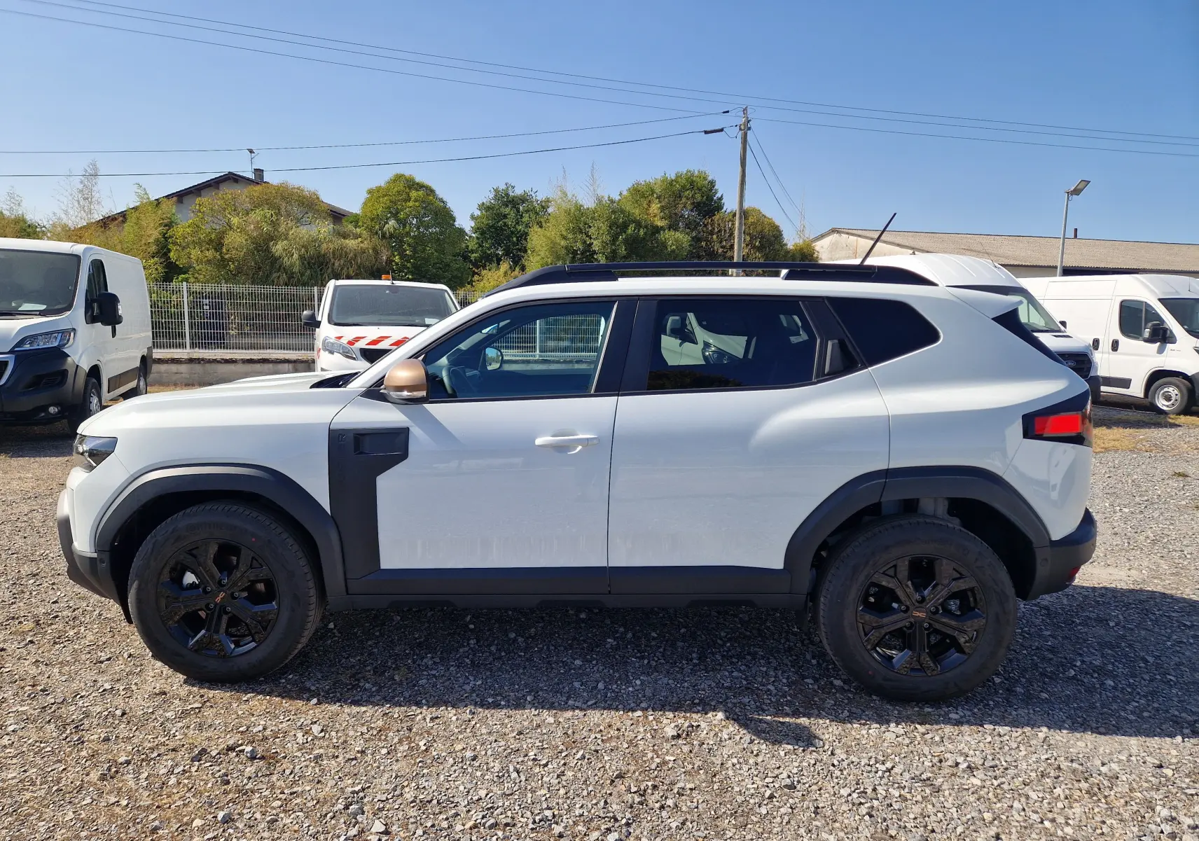 Profil côté gauche du Dacia Duster blanc 2026 avec jantes noires et détails noirs contrastants sur les ailes.