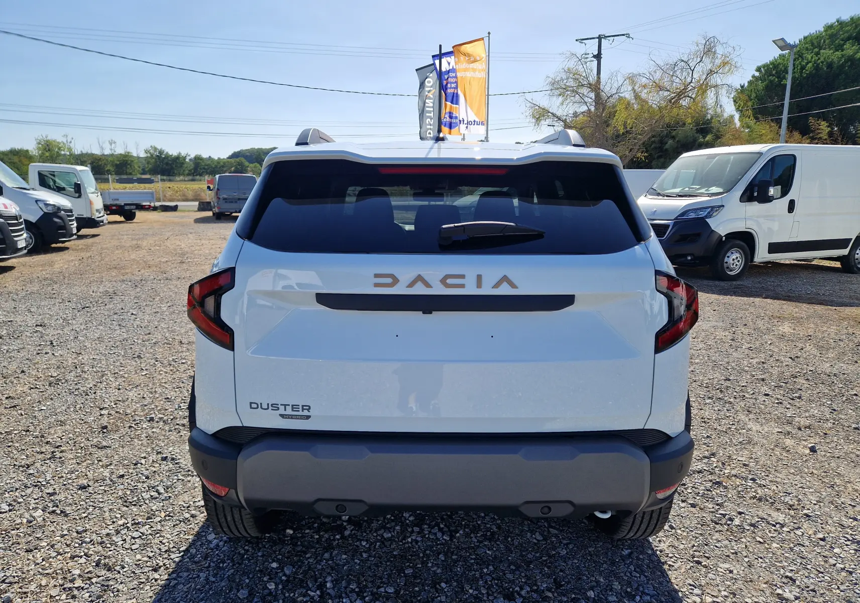 Vue arrière d’un Dacia Duster blanc 2026 hybride, avec logo DACIA en relief et feux arrière anguleux distinctifs.