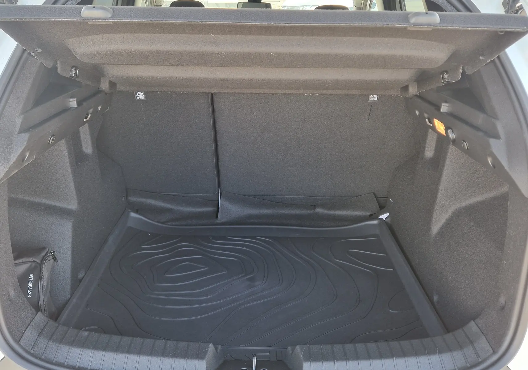 Vue intérieure du coffre ouvert du Dacia Duster blanc 2026, montrant un tapis de protection noir et un éclairage latéral.